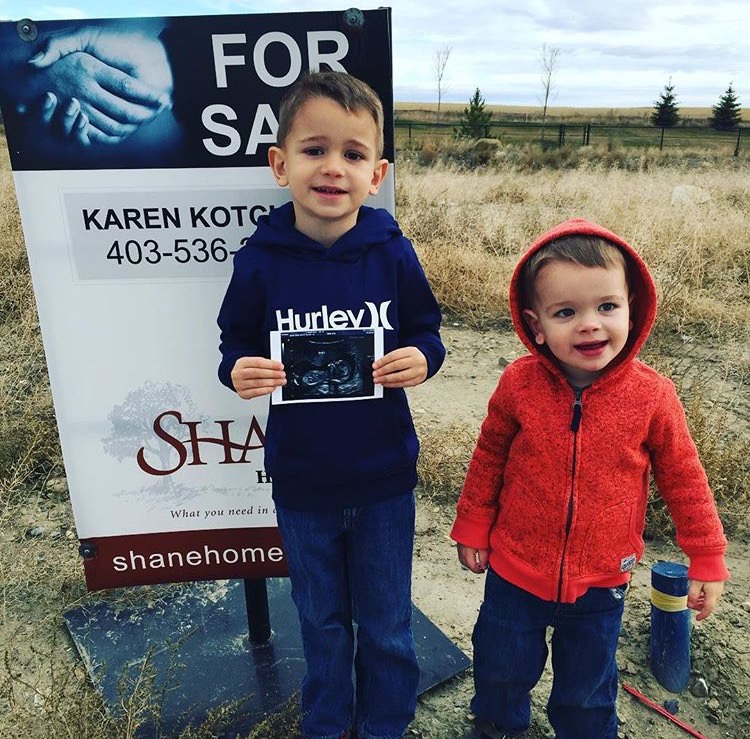 two young children standing in front of a sign