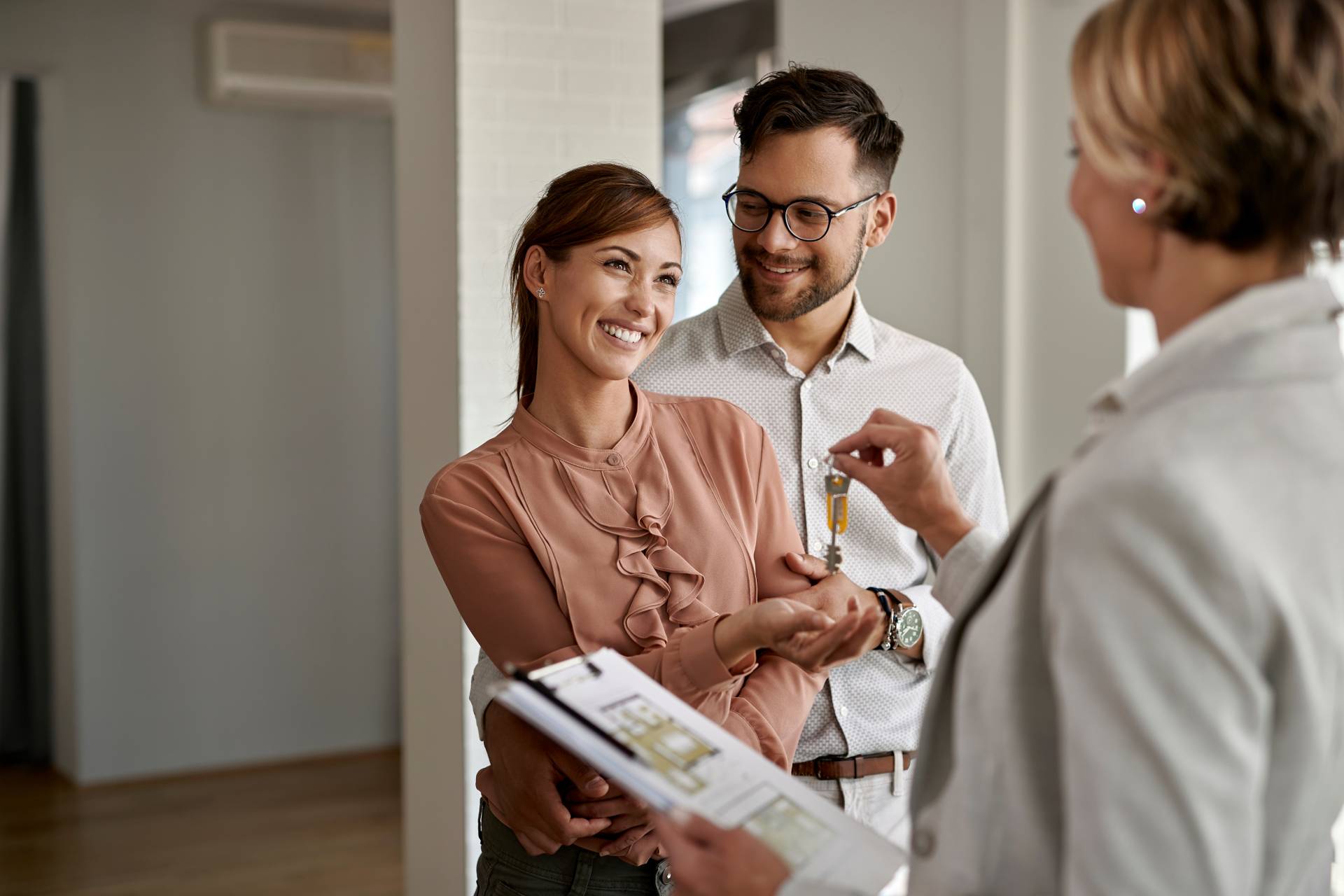 A couple smiling and grabbing keys from an Area Manager.