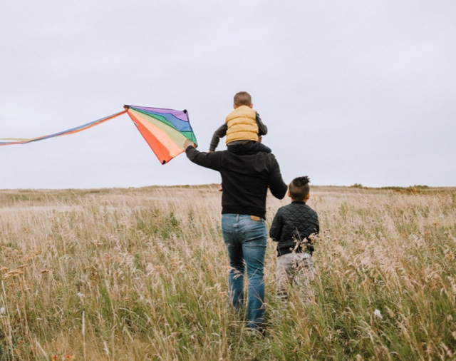 Dad and sons flying a kite.