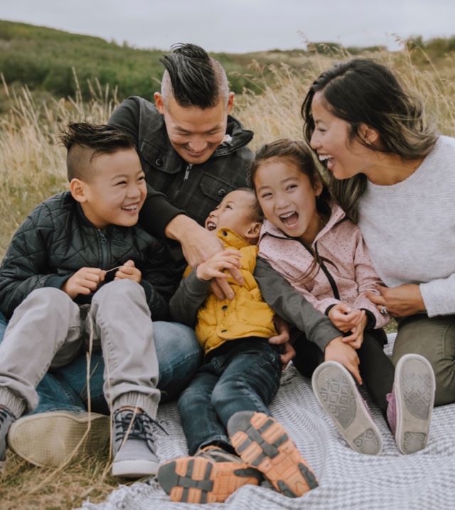 Family sitting in a field laughing.