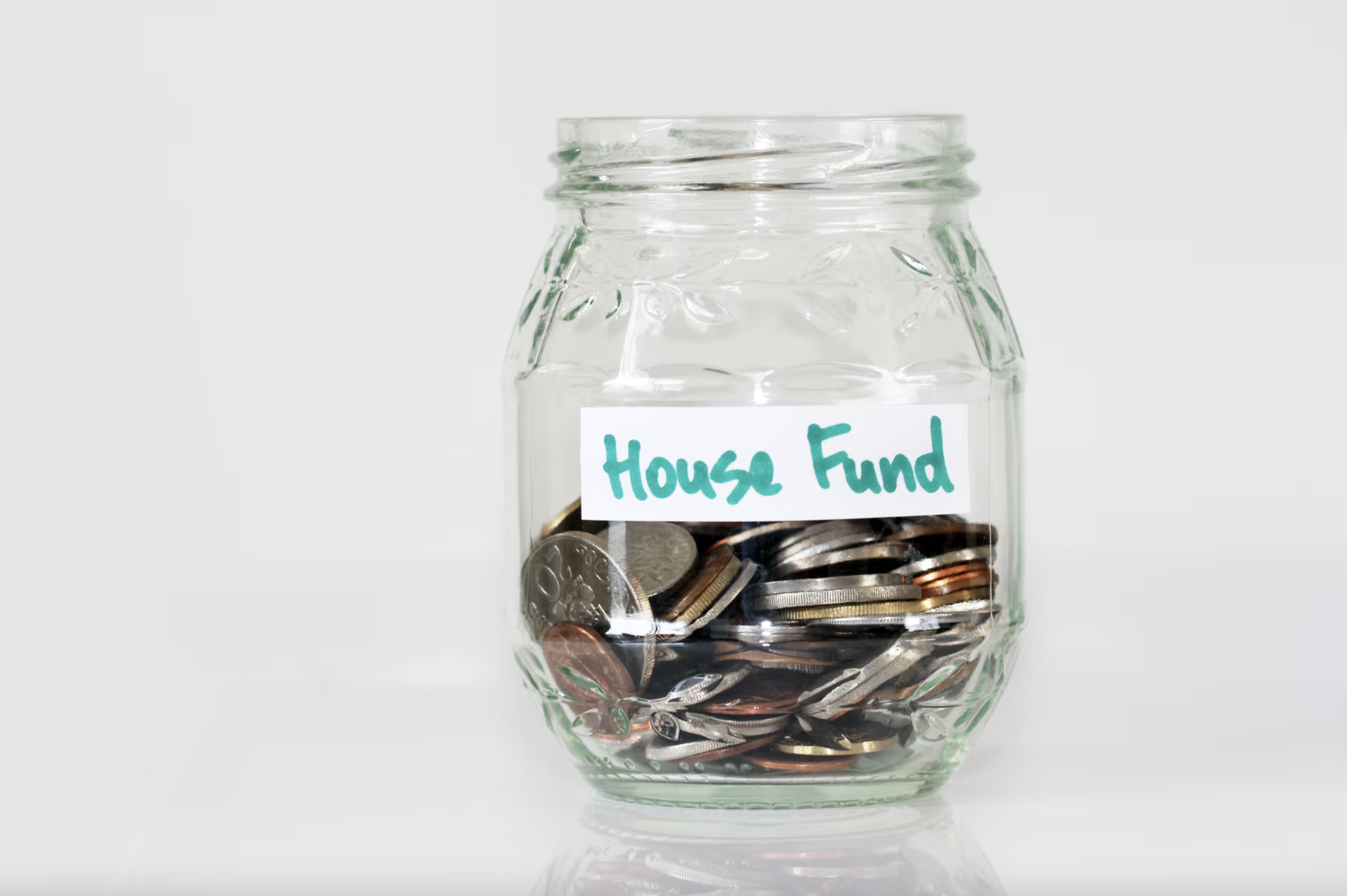Jar of change with tape with the writing “house fund”.