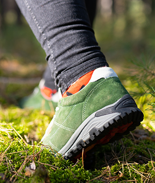 Close up of someone's running shoes trekking through wilderness.