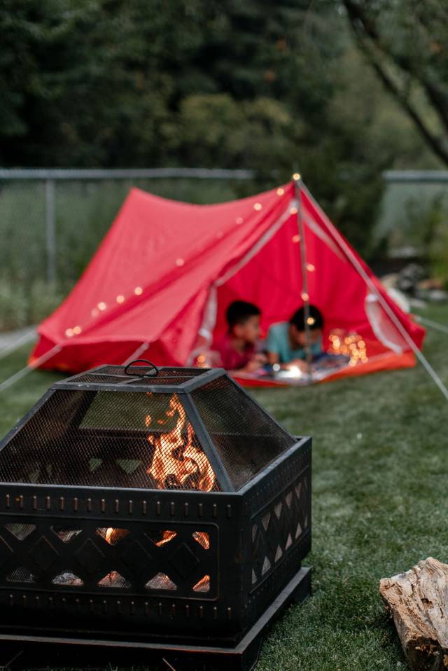 Fireplace in a backyard with kids in a tent.