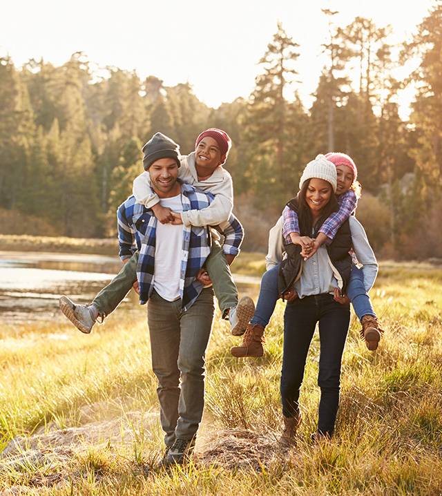 Family piggybacking one another and walking through nature.