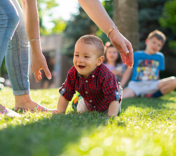 a young child is standing in the grass with a parent