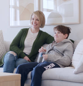 a woman and a child sitting on a couch playing video games