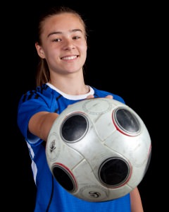 a young girl holding a soccer ball in her hands