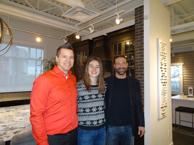 three people standing in front of a home showcase