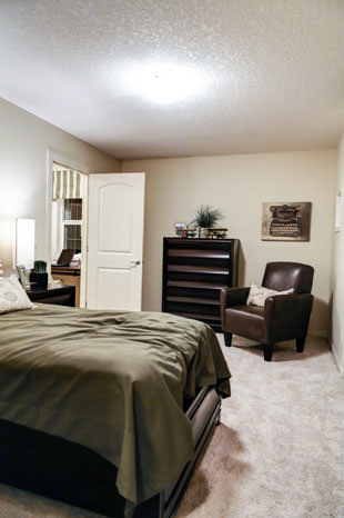 a bedroom with a bed, chair, and a television