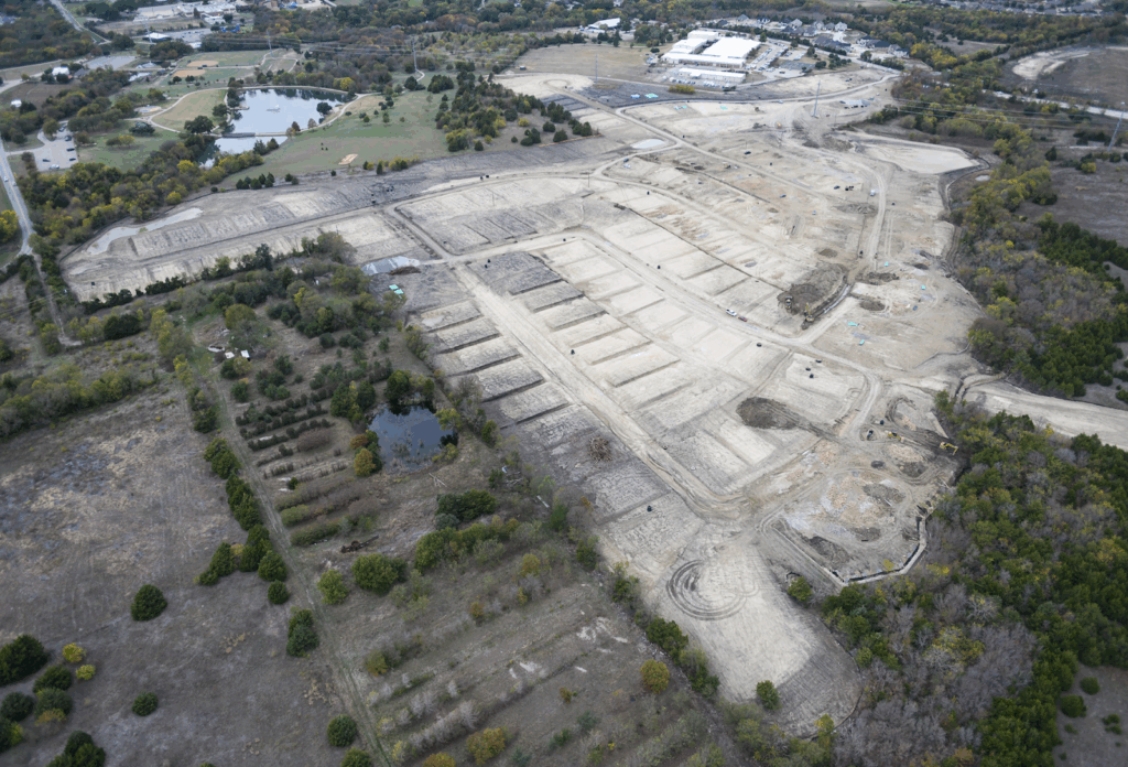Aerial view of a residential construction site with cleared and graded lots, showing early stages of land development before home building begins.