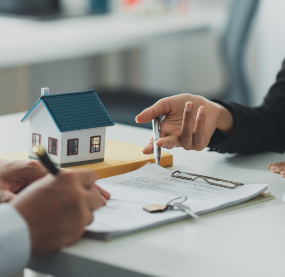 Contract signing with contract papers beside a miniature house