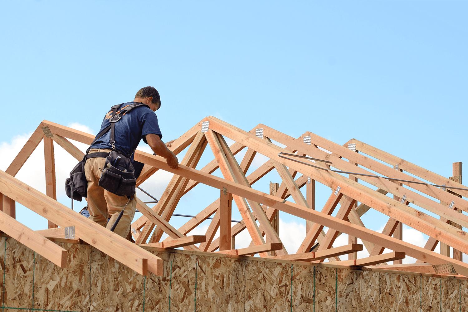 Construction worker framing a roof truss on a new custom home build in Rockwall, TX.