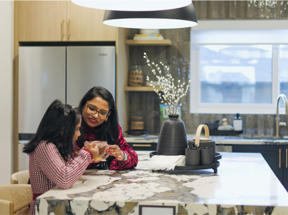 A woman and a girl are seated at a kitchen table, engaged in conversation and sharing a meal together.