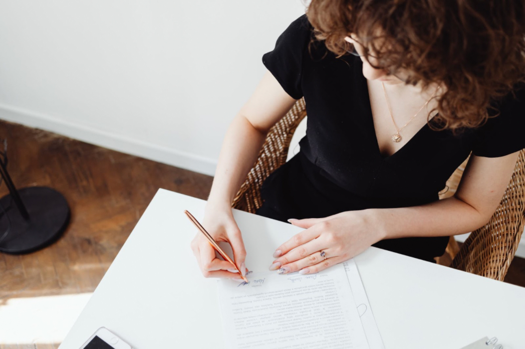 A woman is signing important documents.