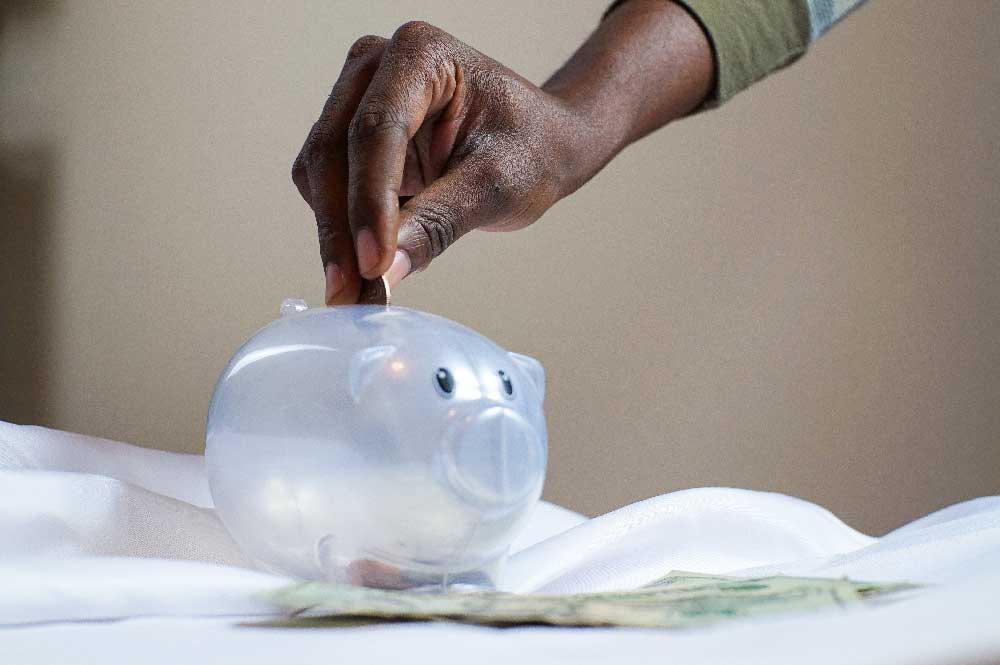 A hand putting money in a piggy bank